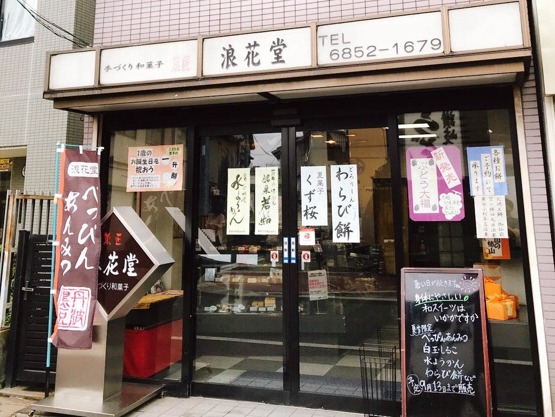 菓匠 浪花堂の店先。ガラス戸に「わらび餅」などの品書きが貼られ、のぼりと黒板が立つ