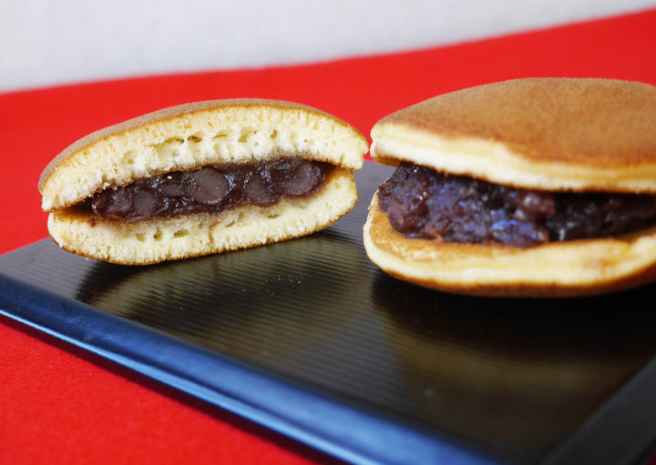 赤い布を敷いた黒い盆に、つぶあんをはさんだどら焼きが二つ